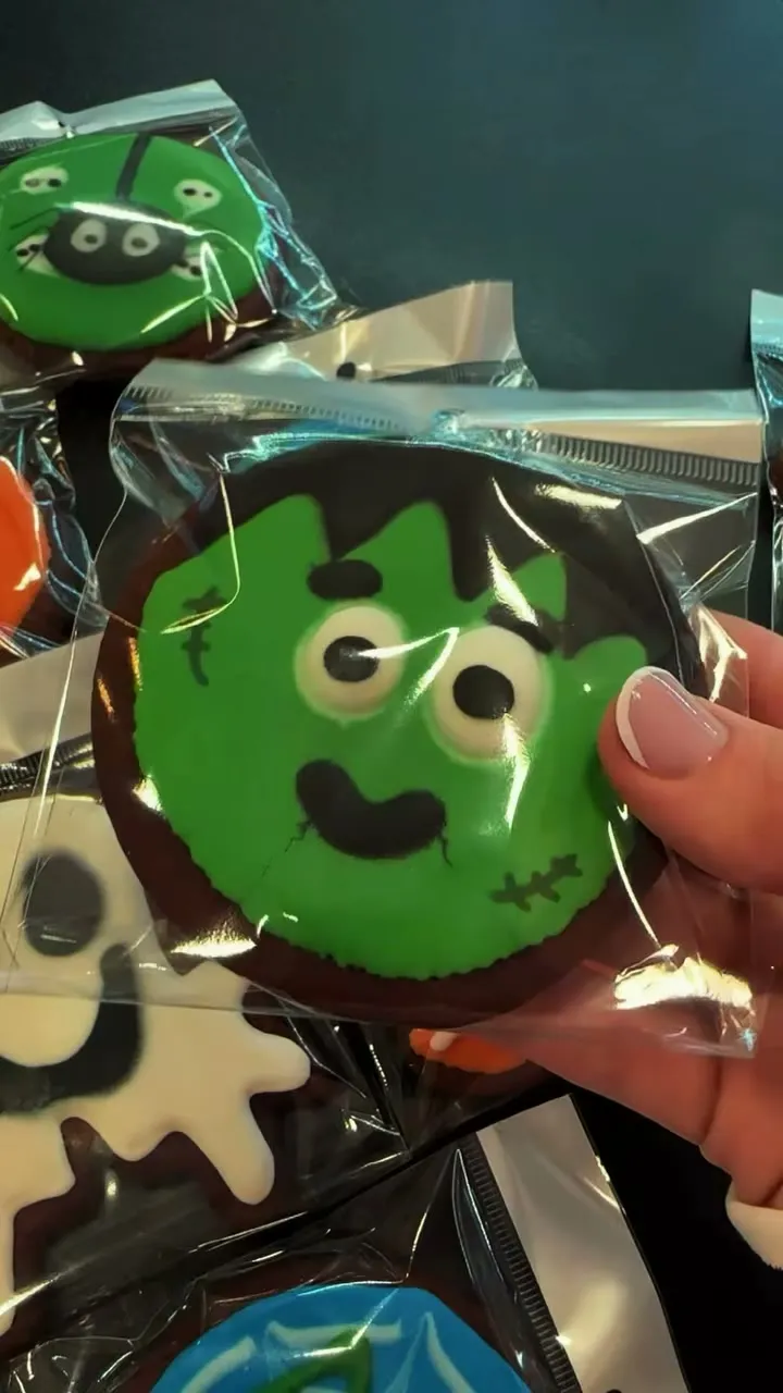 Galleta decorada con la cara verde de un monstruo, envuelta en celofán