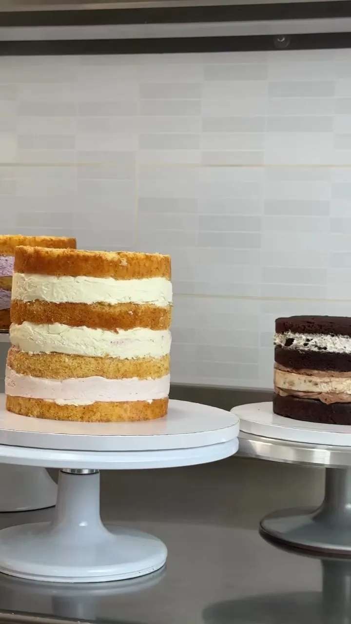Dos tartas por capas sin cubrir, una de vainilla y otra de chocolate, sobre soportes blancos